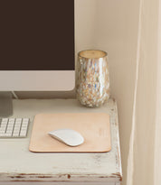 A computer monitor, keyboard, and mouse sit on a white desk next to a marbled glass candle holder, complemented by the Launcher Mouse Pad from Bed|Stü, which elevates this workspace accessory setup.