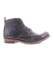 The Bed|Stü Lincoln II is a single dark brown leather lace-up work boot featuring a worn texture, low wooden heel, apron toe, and pull tab at the back, shown in a side view.