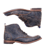 A pair of Bed|Stü Lincoln II distressed dark brown men's boots with apron toes and sturdy wooden soles, displayed from the side and sole views against a white background.