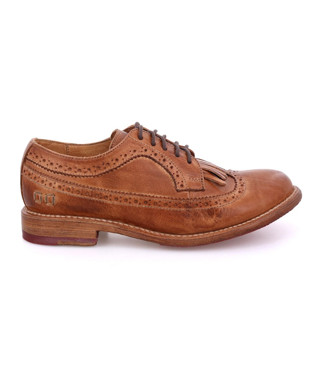 Bed|Stü Lita K brown leather dress shoe, shown in profile on a white background, features a classic wingtip toe, intricate brogue detailing with decorative perforations, laces, and a low heel.