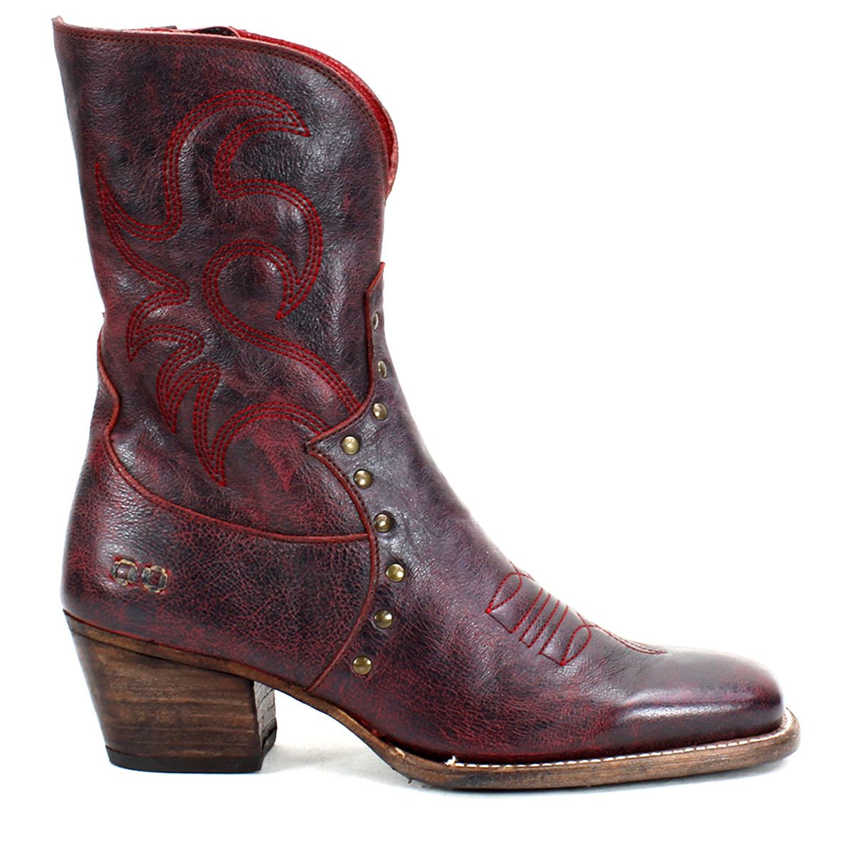 A single Bed|Stü Locate Western boot in dark red leather, featuring decorative flame stitching, metal studs, a low wooden heel, a side zipper, and a slightly worn look.