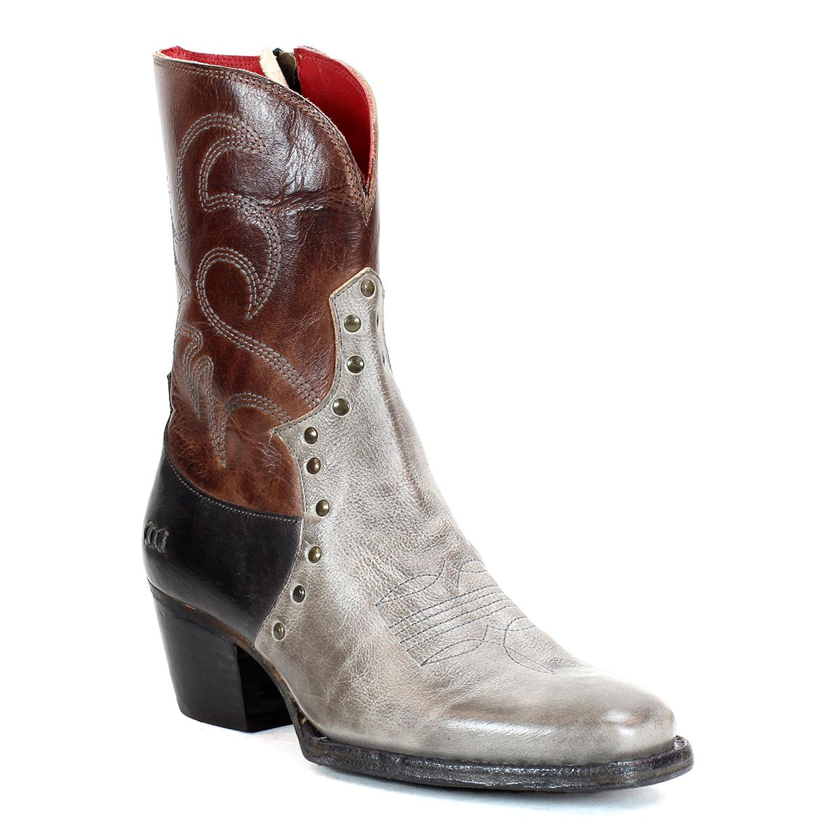 Introducing Locate by Bed|Stü: a single mid-calf Western boot crafted from gray and brown leather, featuring a pointed toe, decorative flame stitching, metal rivets, a convenient side zipper for easy wear, and a chunky black heel.