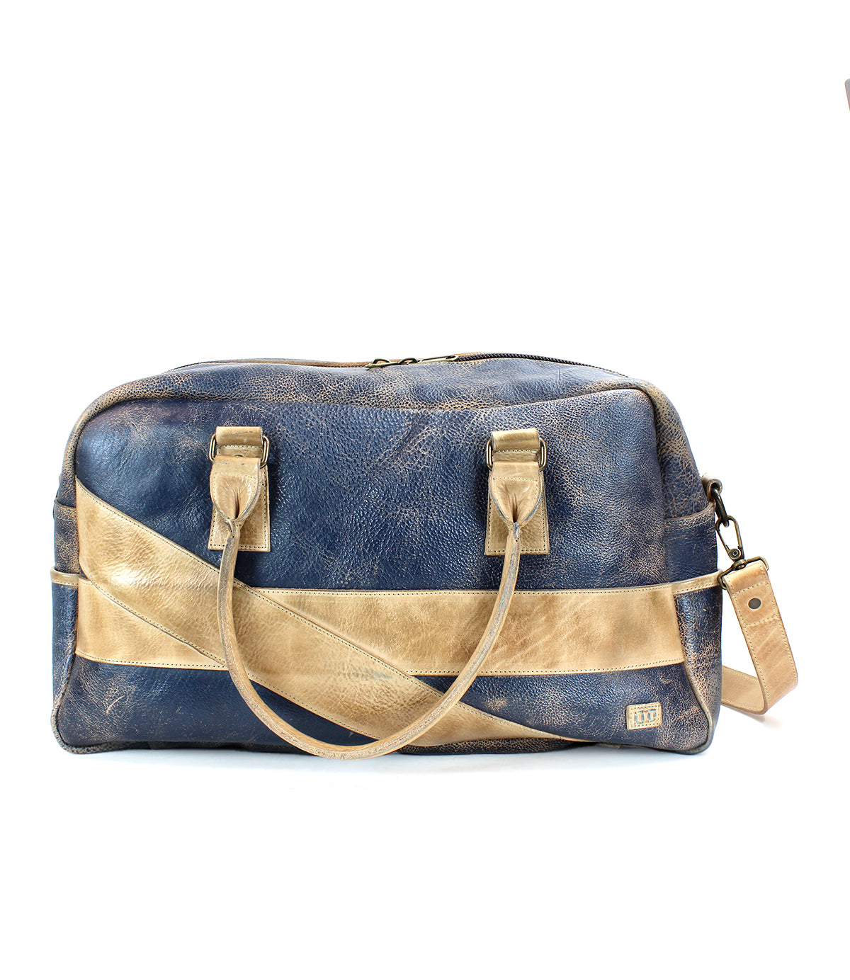 The Luke travel bag by Bed|Stü is an oversized duffle crafted from vegetable tanned leather in blue and tan. Featuring dual handles, a detachable shoulder strap, and a bold diagonal tan stripe, this stylish bag is presented against a white background.
