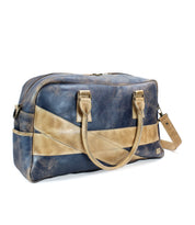 Introducing the Luke by Bed|Stü: an oversized duffle crafted from vegetable-tanned leather in blue and beige, featuring two sturdy handles, a convenient shoulder strap, and a striking diagonal beige accent—making it the perfect stylish travel companion.