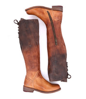 The Bed|Stü Manchester tall leather boots in rich brown, featuring comfortable flat heels, side zippers, and a back lace-up detail, are shown lying side by side on a white background.