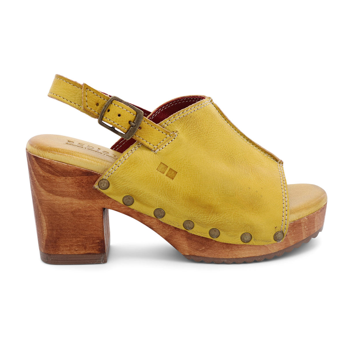 The Marie sandal by Bed|Stü is crafted from vegetable tanned leather in yellow, featuring an open toe, a wood platform heel inspired by classic heeled clogs, metal studs, and an adjustable ankle strap with buckle.