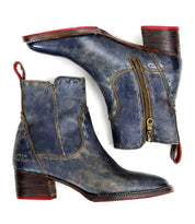 A pair of worn blue leather "Merryli" boots by Bed|Stü, featuring square toes, side zippers, red pull tabs, and low stacked wooden heels. These hand-stitched boots are shown from the side and bottom.