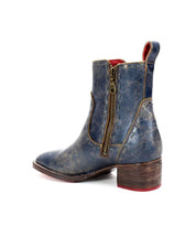 Side view of the Bed|Stü Merryli worn blue leather ankle boot, featuring a brown wooden heel, visible hand-stitched details, and a brass side zipper, shown against a white background.
