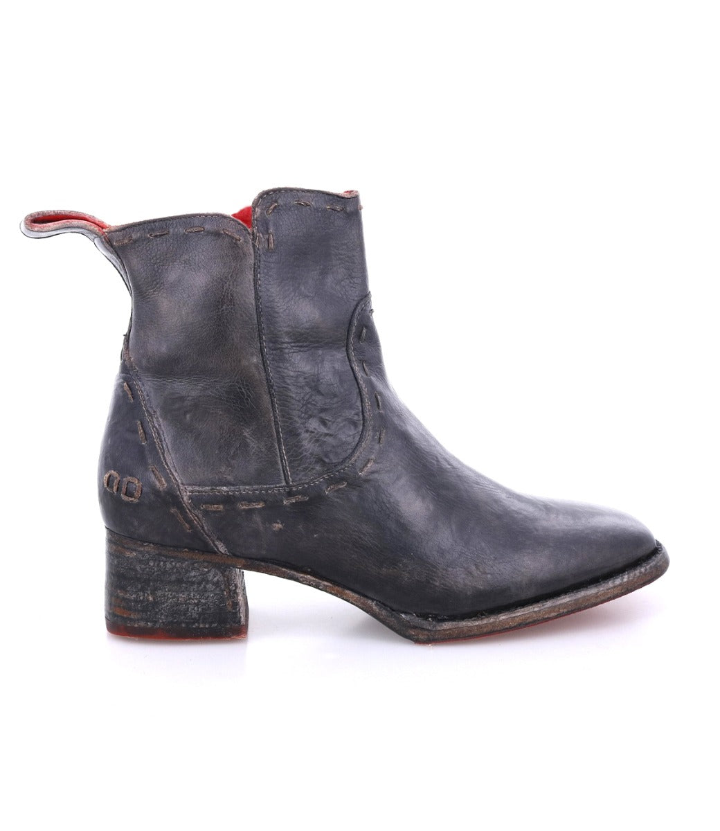 The image displays the Merryli ankle boot by Bed|Stü—a handcrafted black leather boot featuring a low heel, classic square toe, visible stitching, red inner lining, and a pull tab at the back, all set against a white background to highlight its artisanal quality.