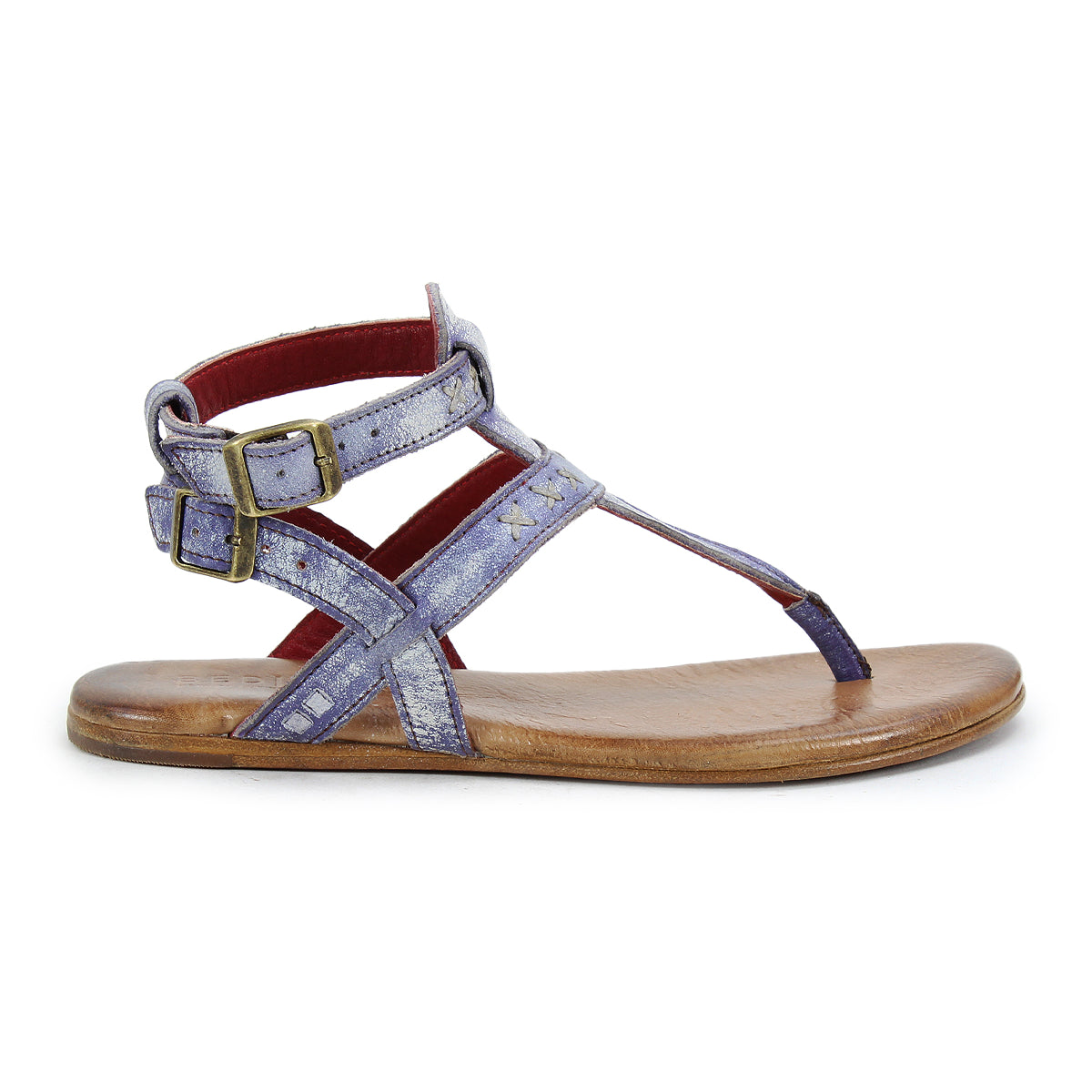 The Bed|Stü Moon sandal is a single flat design featuring metallic purple leather straps, dual brass ankle buckles, a cushioned insole, brown sole, and back ankle support, shown in profile on a white background.