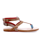 The Bed|Stü Moon sandal is shown in side profile against a white background, featuring tan leather construction, two ankle straps with metal buckles, a blue toe loop, and a cushioned insole.