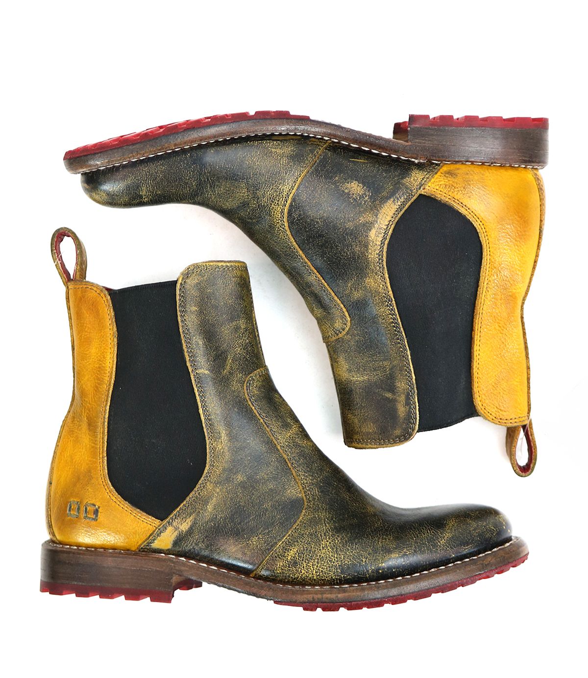 Introducing the Bed|Stü Nandi—a pair of leather Chelsea boots featuring a striking black and yellow distressed finish, black elastic side panels, red pull tabs, bold red rubber soles, and classic brown midsoles. With their timeless slip-on design, the Nandi boots are versatile footwear essentials suited to any occasion.