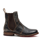 The Bed|Stü Nandi is a single worn black leather Chelsea boot with brown elastic side panels and a pull tab at the back, featuring a classic slip-on design, shown in profile on a white background.