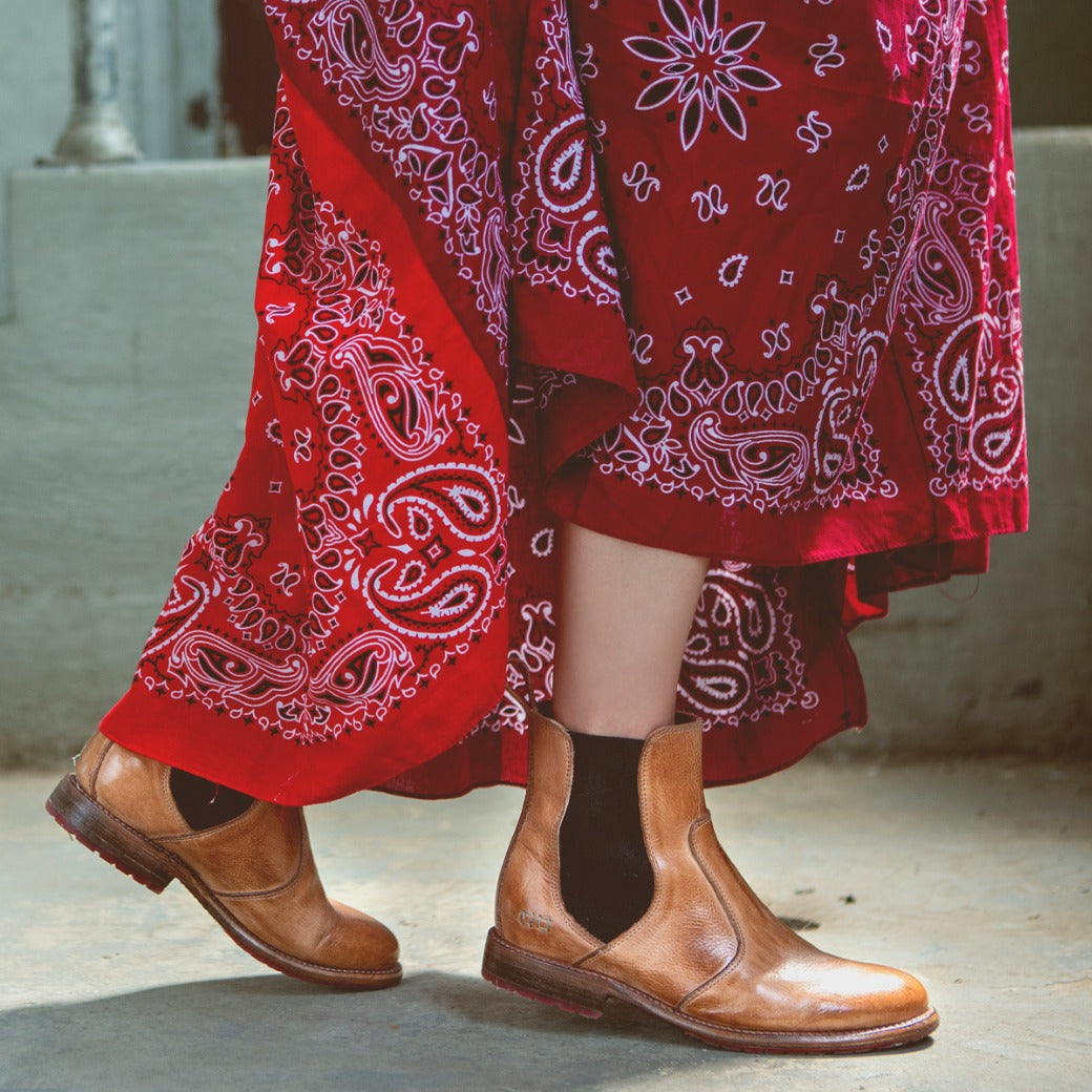 A person stands on a concrete floor wearing a red patterned skirt and the Bed|Stü Nandi boots—celebrated for their slip-on design.
