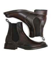 Bed|Stü Nando pair of dark brown hand-worked leather Chelsea boots with black elastic side panels and pull tabs, featuring Goodyear welt construction, shown from side and sole views on a white background.