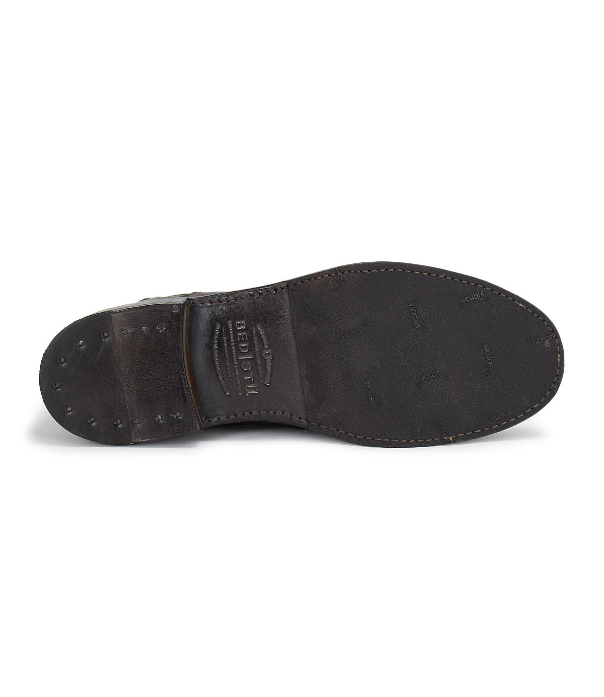 The image shows the sole of the Bed|Stü Nando, a dark brown leather dress shoe featuring visible stitching and metal tacks in the heel area, which highlight its Goodyear welt construction—a hallmark of high-quality, hand-crafted footwear.