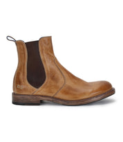 The Bed|Stü Nando is a tan hand-worked leather Chelsea boot featuring dark elastic side panels, a pull tab at the heel, and a low stacked heel, shown from the side on a white background.