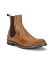 The Bed|Stü Nando is a brown leather Chelsea boot with a rounded toe, low heel, elastic side panels, and a pull tab at the back. Expertly crafted from hand-worked leather and featuring durable Goodyear welt construction, it is shown here on a white background.