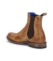 The Nando Chelsea boot by Bed|Stü is crafted from hand-worked brown leather and features elastic side panels, a blue inner lining, and a pull tab. Shown from a rear side angle on a white background, this classic silhouette is finished with a durable Goodyear welt for lasting quality.