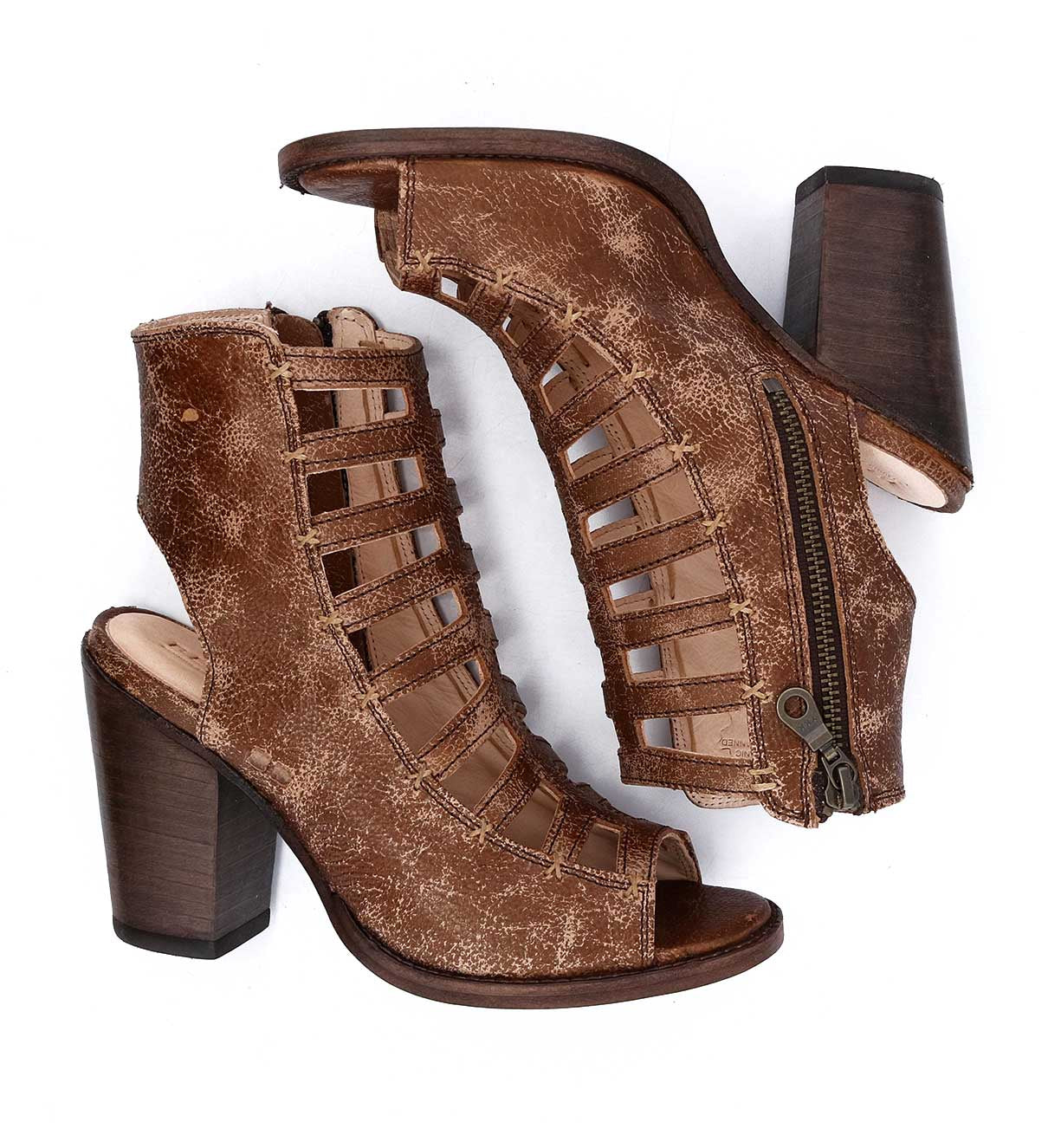 A pair of Bed|Stü Occam P brown distressed leather heeled sandals featuring open toes, cut-out sides, decorative X stitching, block heels, and visible side zippers, displayed on a white background.