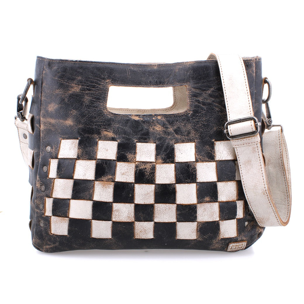 The Orchid shoulder bag by Bed|Stü features a modern, timeless design with its distressed, handwoven leather in a checkerboard black and white pattern. This stylish accessory offers a rectangular cutout handle, an adjustable strap, and is accented with an antique metal buckle for added flair.
