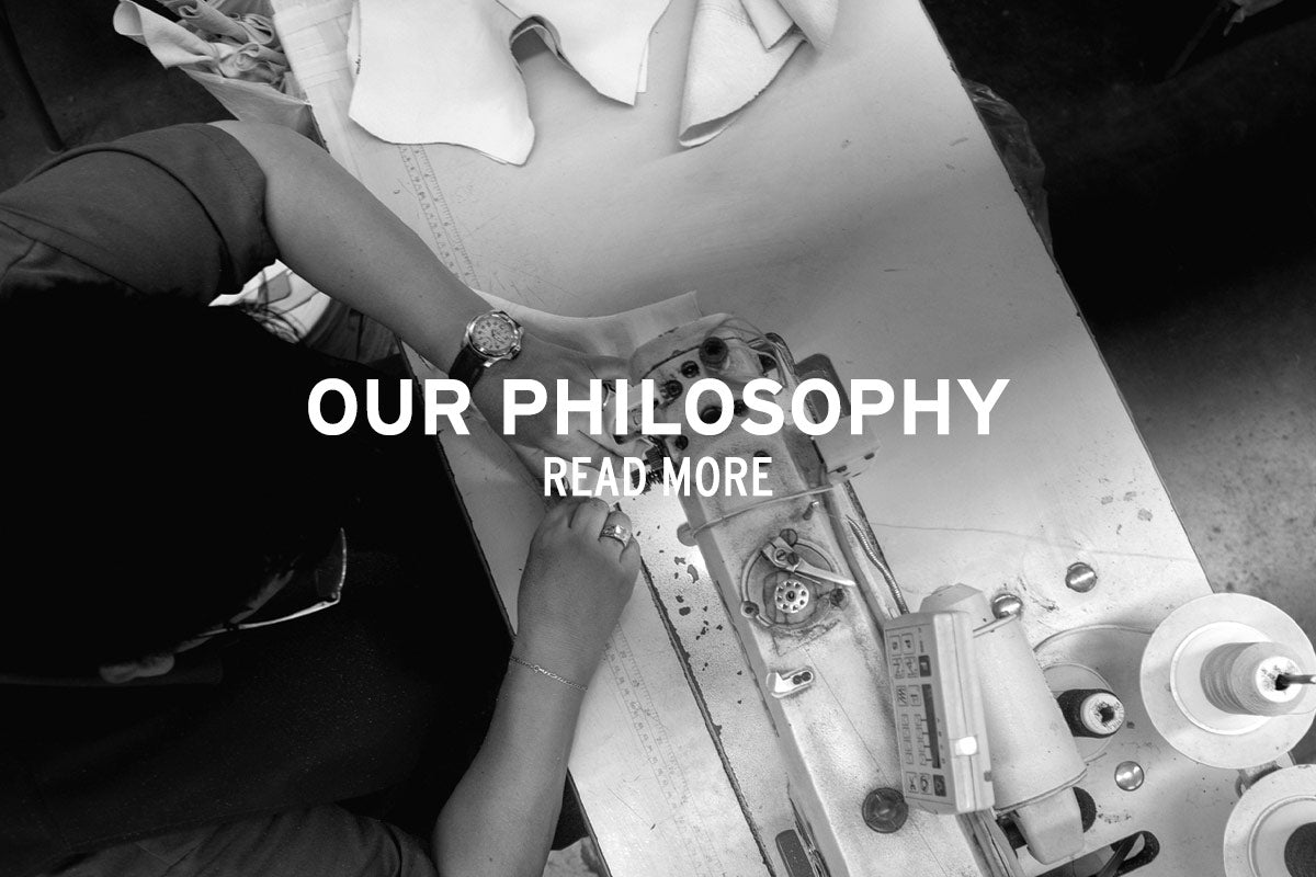 Black-and-white banner showing a person sewing material at a worktable, with the text “Our Philosophy” and “Read More.”