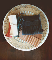 Bed|Stü’s Prepped Leather Wraps are stylish leather organizers, perfect for artists, displayed on a woven placemat atop a round white table.