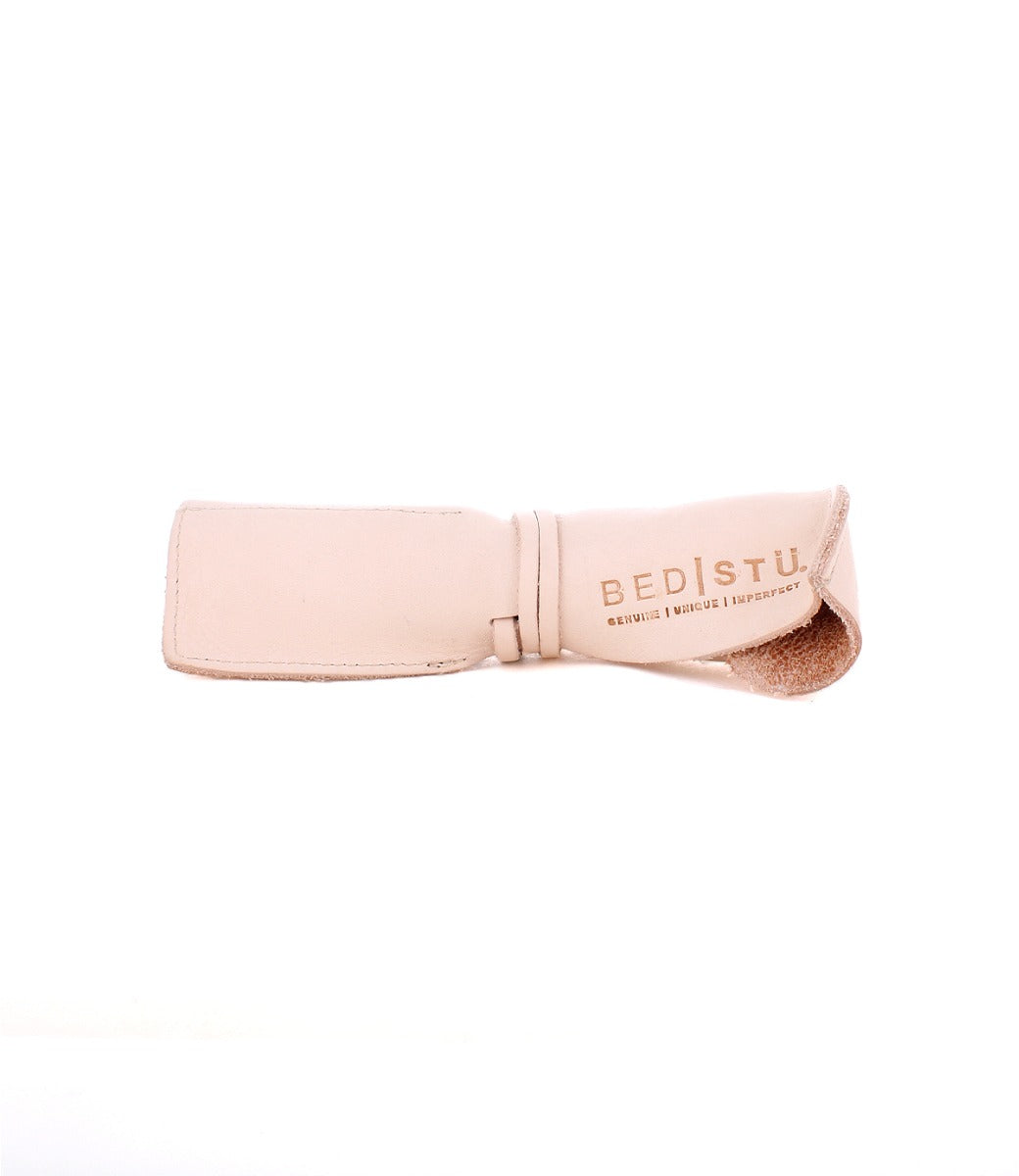 A light beige Prepped Leather Wrap eyeglass case by Bed|Stü, featuring a leather wrap design and "BED|STU GENUINE UNIQUE IMPERFECT" printed on the flap. Displayed against a plain white background, this stylish organizer is perfect for artists and creatives alike.