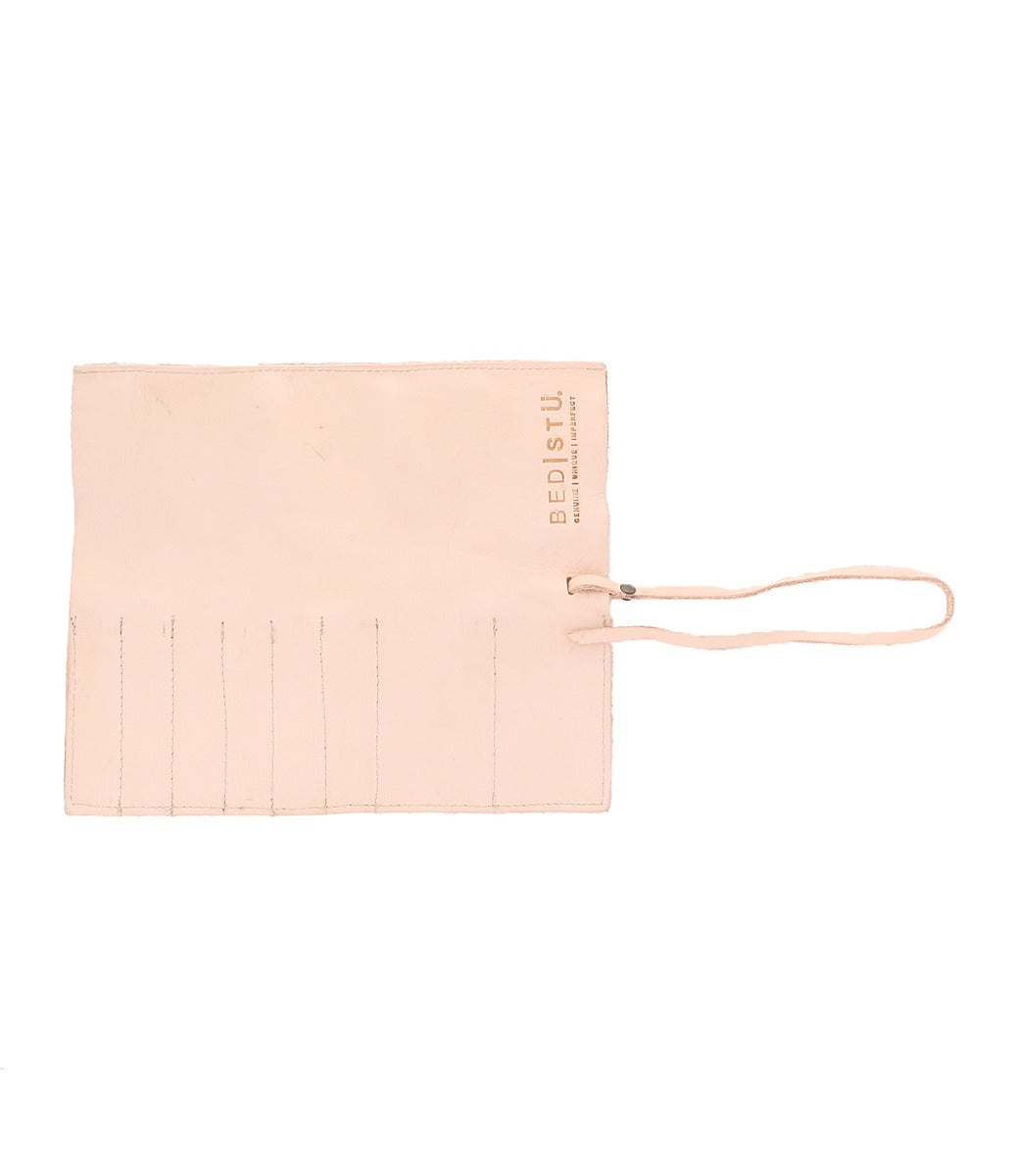 The Prepped Leather Wrap by Bed|Stü is a beige leather tool or brush roll featuring stitched slots and a tie closure, designed as an elegant organizer for artists, with the Bed|Stü logo in the top right corner.