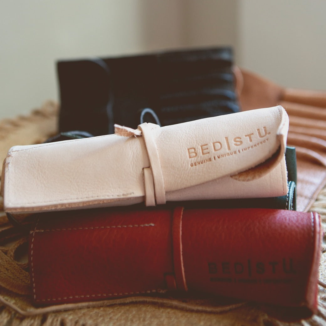 Stack of three Prepped Leather Wraps by Bed|Stü in light pink, dark, and red—an ideal organizer for artists. The light pink wrap features "BED STU" embossed on it.