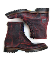 A pair of Bed|Stü Protege Trek distressed red leather combat boots with rugged soles and a classic Goodyear welt, shown side by side against a white background.