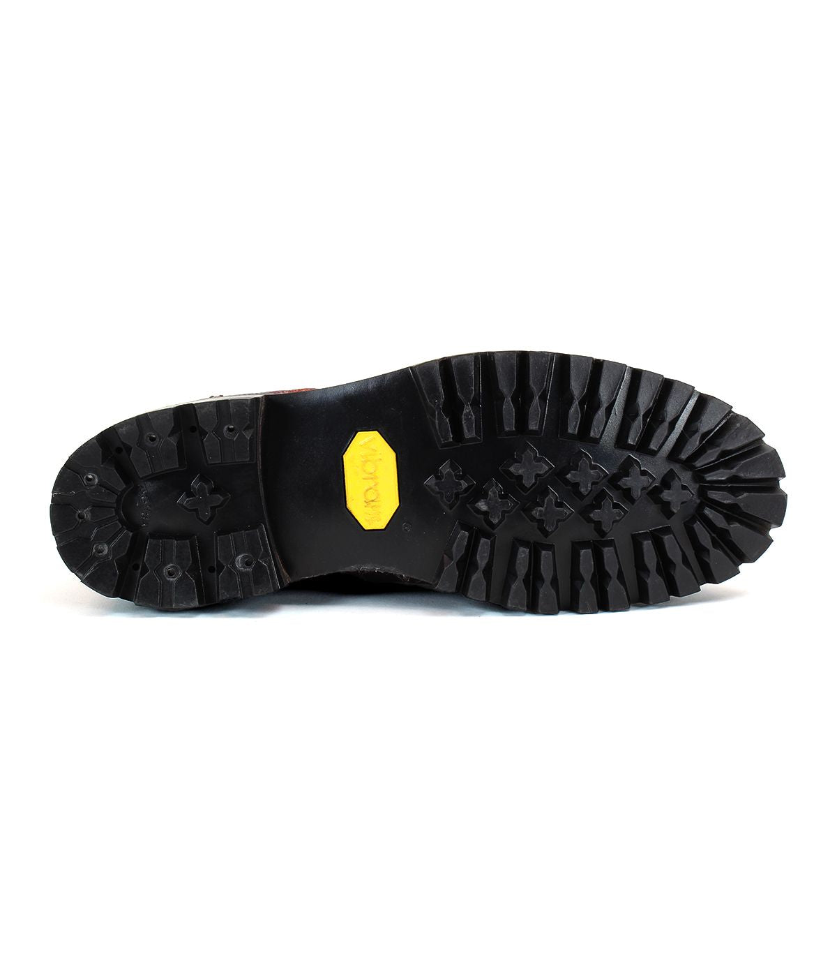 The image shows the black rubber treaded sole of the durable Bed|Stü Protege Trek boot, featuring a yellow hexagonal Vibram logo at the center.