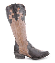 The Bed|Stü Queen boot is a brown and black leather Western-style boot, featuring decorative stitching, elegant fleur-de-lis details, a pointed toe, and a low stacked heel. Crafted from vegetable-tanned leather, it is shown from the side against a white background.