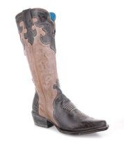 Introducing Queen by Bed|Stü—a tall Western boot crafted from black and tan vegetable-tanned leather, featuring intricate stitching, a pointed toe, a short heel, and subtle fleur-de-lis accents in a striking two-tone design.