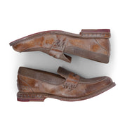 Two worn brown leather Reina penny loafers by Bed|Stü, featuring Goodyear welted construction, are positioned heel to toe on a white background, highlighting visible creases, rich texture, and scuff marks on the leather upper.