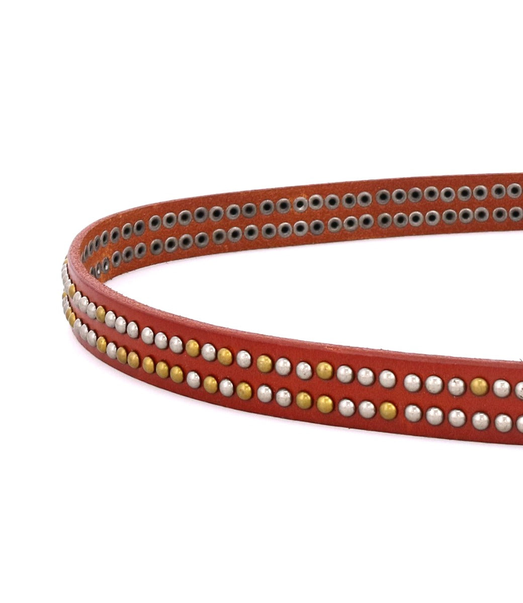 A close-up of the Rico weekend belt by Bed|Stü, crafted from red leather and embellished with two rows of round silver and gold metallic studs.