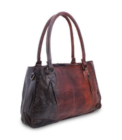 Introducing the Rockaway by Bed|Stü—a brown handbag expertly crafted from full-grain leather. Featuring double handles, decorative edge stitching, and distinctive side tassel accents, this bag seamlessly combines everyday practicality with timeless elegance, all showcased against a crisp white background.