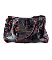 The Bed|Stü Rockaway is a large, dark brown full-grain leather handbag featuring two handles, a front zipper pocket, and subtle surface creases—crafted for everyday function.