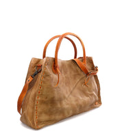 The Bed|Stü Rockaway is a tan full-grain leather handbag featuring two rounded handles, decorative stitching along the sides, and an adjustable shoulder strap, designed for everyday use and displayed on a white background.