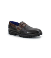 A dark brown leather men's penny loafer called "Samosa" by Bed|Stü, featuring a penny strap and chunky black rubber sole, shown angled to display the outer side and front.