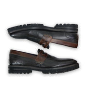 Two Samosa loafers by Bed|Stü in black and brown leather, featuring rugged black soles and a classic loafer design, are placed parallel to each other on a white background.