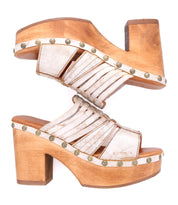 A pair of Bed|Stü Shantel women's platform sandals with wooden heels, metallic silver straps, and metal stud accents, featuring a cushioned leather insole for added comfort, arranged sole to sole on a white background.
