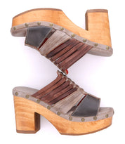 Two Bed|Stü Shantel wooden platform sandals featuring smooth leather straps and a cushioned leather insole are arranged heel to toe, forming an hourglass-like shape against a white background.