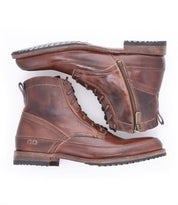 A pair of Spiker boots by Bed|Stü, crafted in brown leather with lace-up fronts and side zippers, are stacked one on top of the other against a white background. These men’s boots also feature a cushioned insole for added comfort.