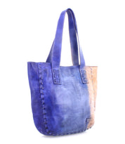 Introducing the Stevie by Bed|Stü—a leather tote bag with wide handles, featuring a striking blue-to-tan gradient design and visible stitched seams along the sides and base. Perfect for everyday carry or anyone seeking a touch of vintage bag charm.