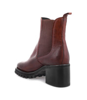 Introducing Surge by Bed|Stü—a brown Italian leather Chelsea boot featuring a chunky black heel and a treaded sole, displayed from an angled rear side view.