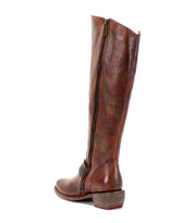 The Bed|Stü Takoma is a tall brown leather boot with a side zipper, low western-shaped heel, slightly worn finish, and an asymmetrical top, shown from a side angle on a white background.