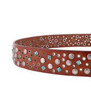 The Tammin II belt by Bed|Stü is a brown leather accessory adorned with silver studs and turquoise-colored square accents, shown against a white background.