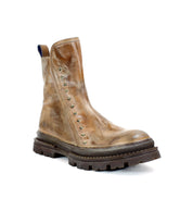 The Bed|Stü Tanto is a brown leather Chelsea boot adorned with metal studs along the side, showcasing a streamlined silhouette, chunky treaded lug outsole, and a pull tab at the back, displayed against a white background.