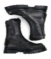 A pair of Tempt black lace-up combat boots by Bed|Stü, featuring thick, rugged soles and a sleek Chelsea boot silhouette—shown side by side and stacked—these stylish hybrids offer the durability of hiking boots with modern design, set against a white background.